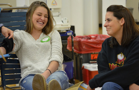 Senior Kaylin Williams laughing with leadership adviser Sarah Green to get her mind off of blood, as she donates at the school blood donation on November 14.