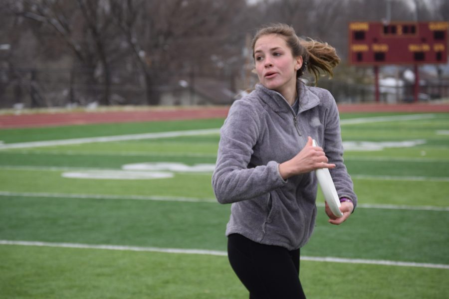 Senior+Cayla+Adamson+spins+around+while+holding+the+frisbee+in+order+to+throw+it+to+another+teammate.