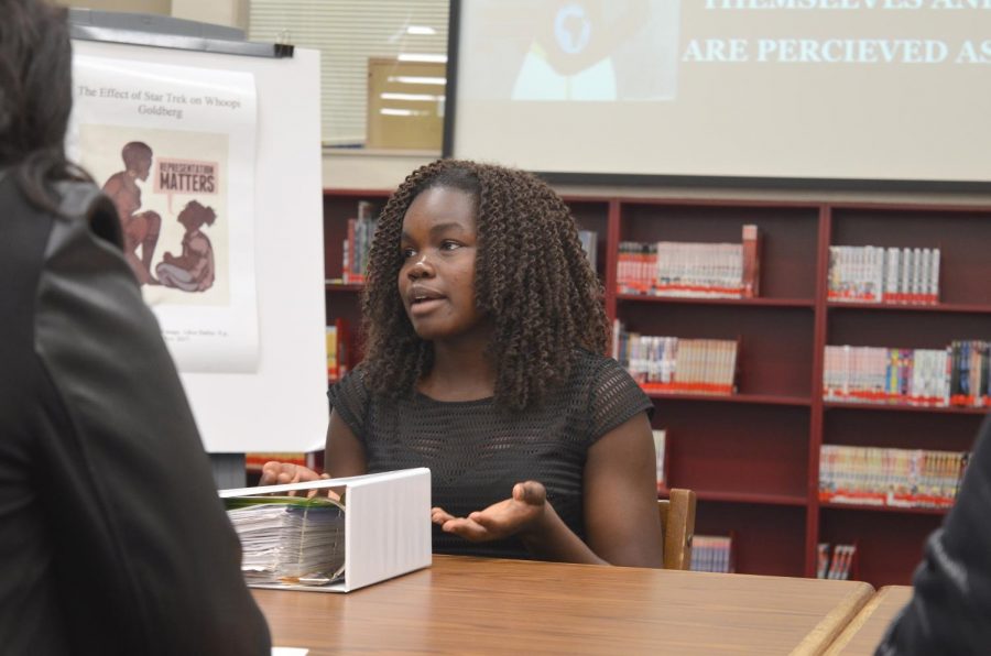 Senior Vaida Juma presents her Gold Medallion exhibition project about the media representation of black women in the library on Dec. 7. 