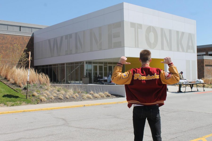 Aksels proudly stands in front of Winnetonka after the building is closed due to a stay-at-home order. In the background, staff members work hard to prepare food packages for the families they serve. This is his final photo.